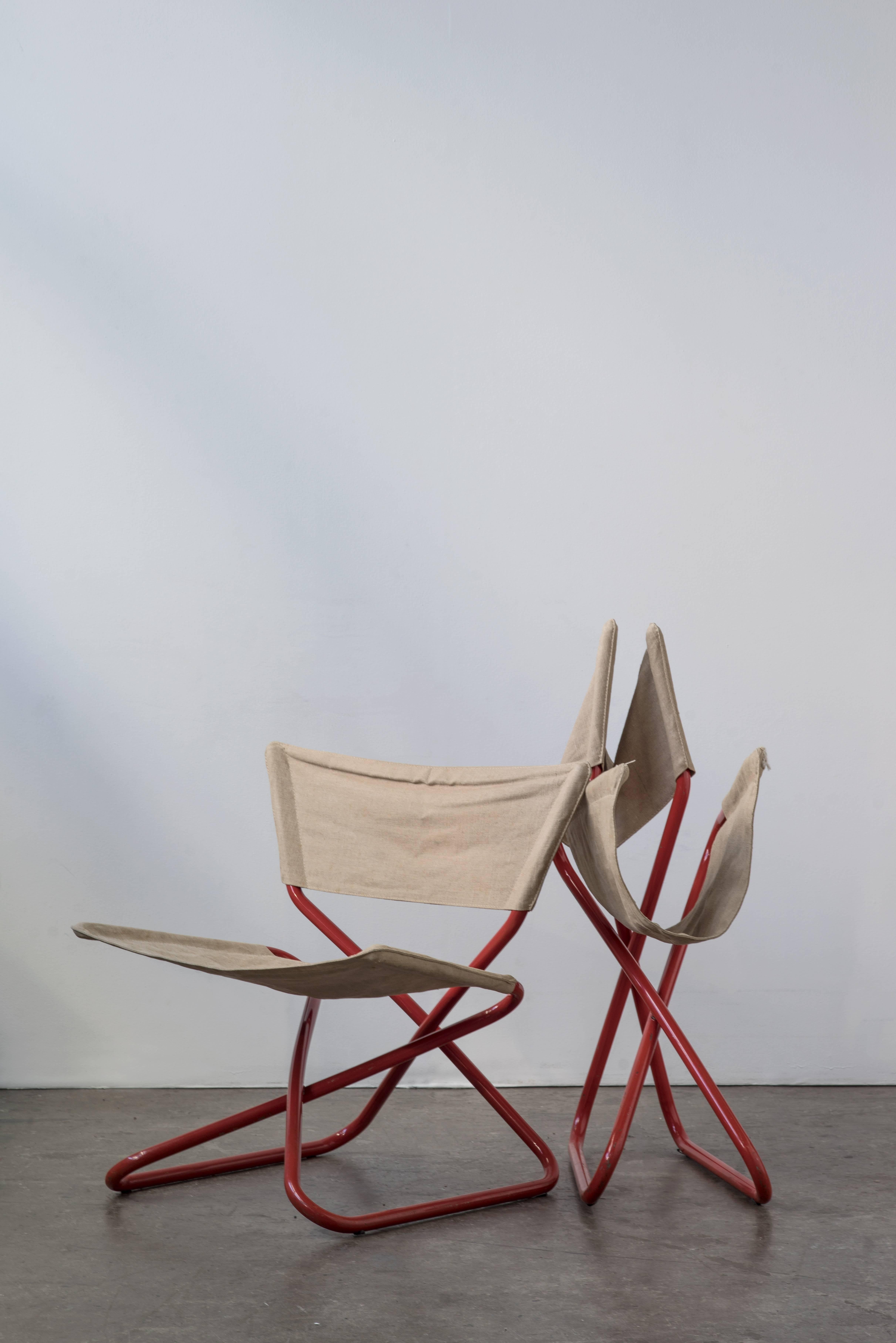 Pair of folding Z-down lounge chairs by Erik Magnussen in red lacquered tubular steel frames with canvas seat covers.

Durable, comfortable and practical with a little bit of a rocker effect in the seats as you sit. 

Could be used indoors or