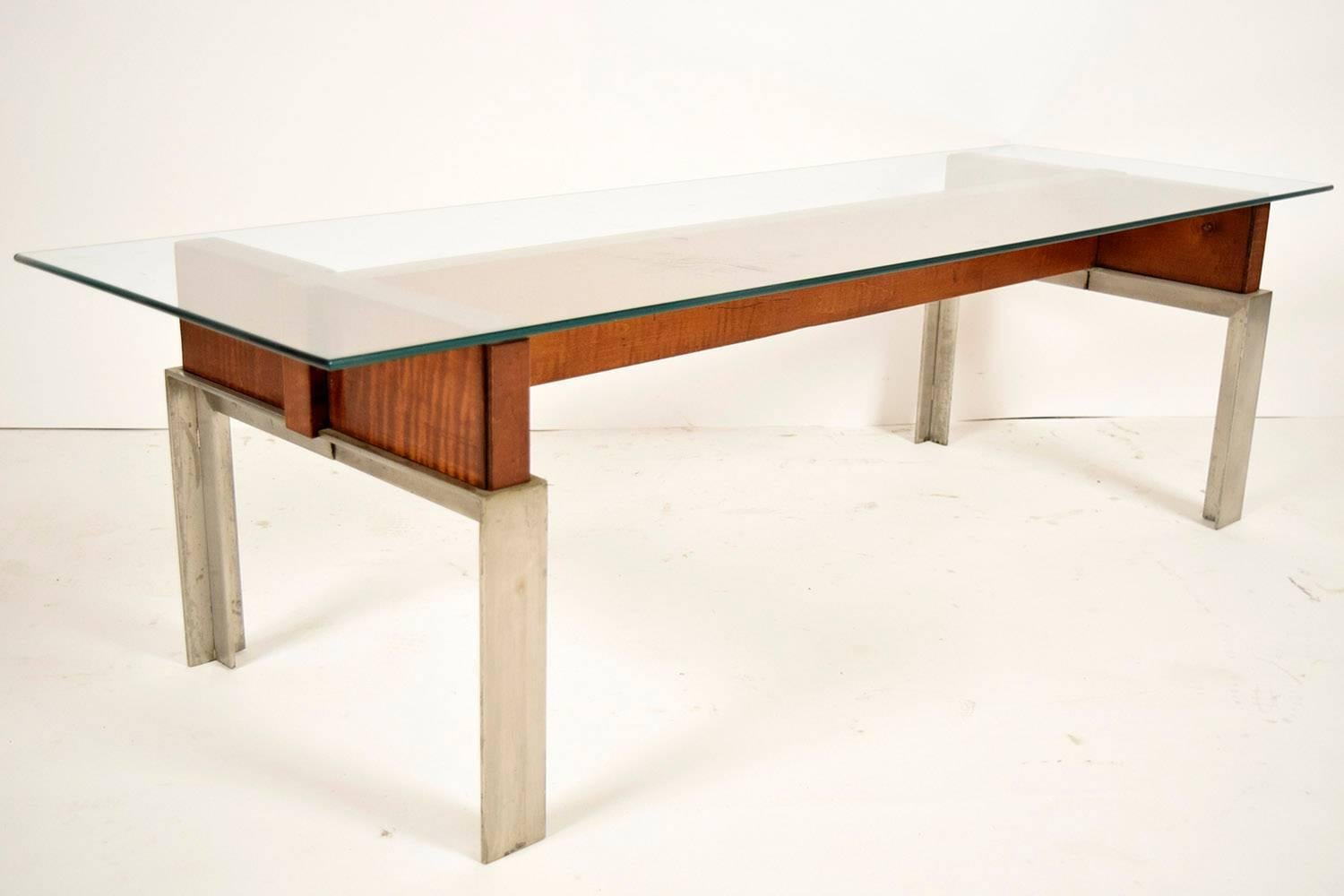 This is a beautiful 1970's Mid-Century Modern-style coffee table that will be a great addition to any room. The table has a clear glass top with a pencil polish and rests upon an H-shaped wooden frame. The gorgeous wood is complemented by four