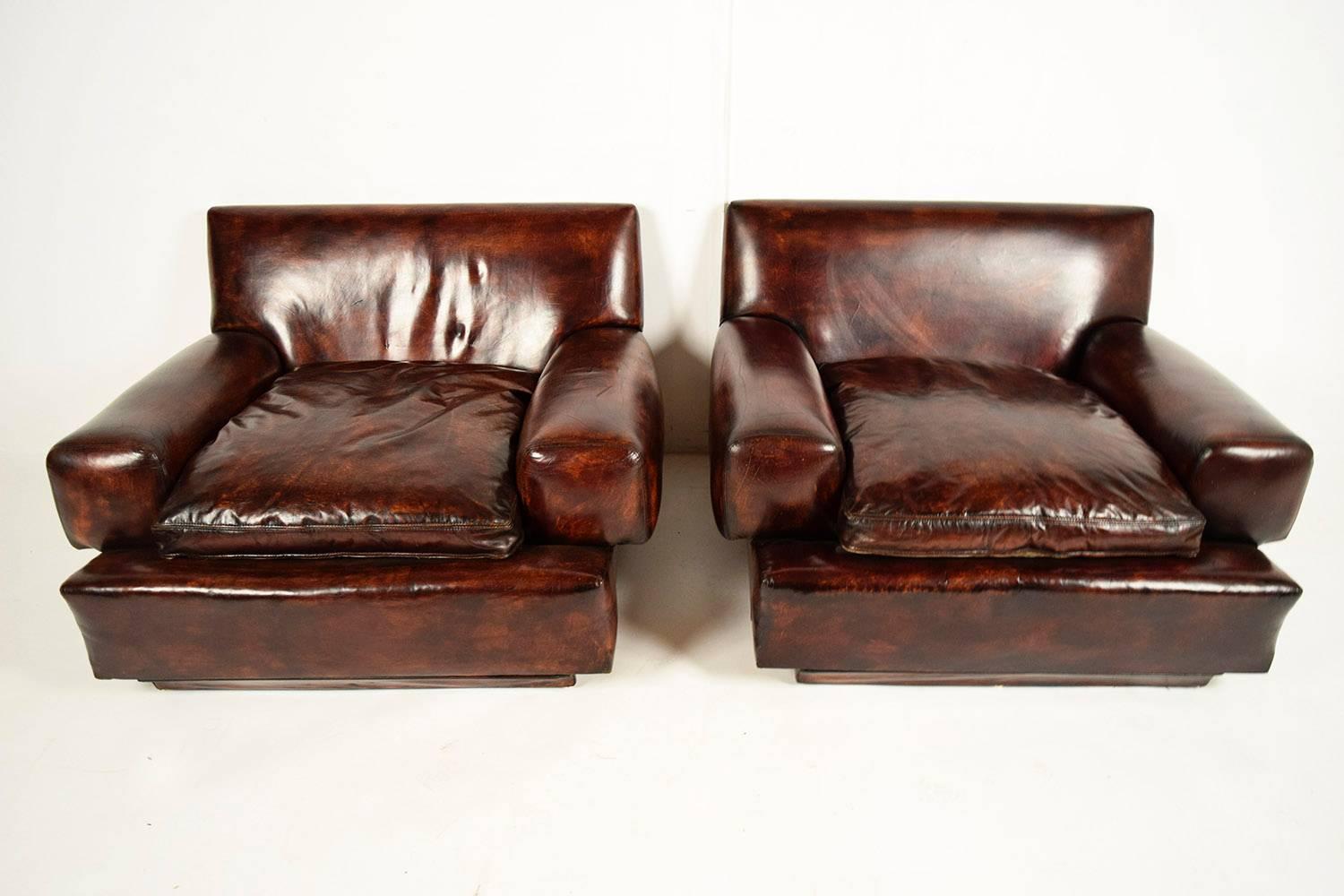 Pair of low 1960s modern leather club chairs. Wood frame, covered in dark brown leather with a beautiful distressed finish, showing amazing patina. Chairs have a loose cushion with matching color and distressed finish. Both chairs are solid and