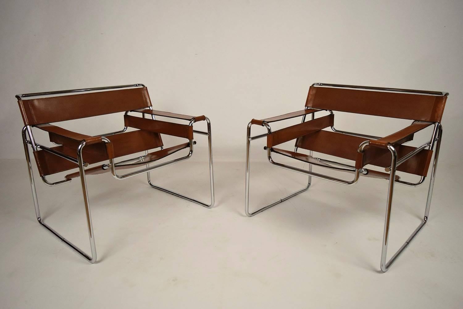 This pair of 1970's vintage Wassily chairs were designed by Marcel Breuer. The chairs feature a uniquely shaped chrome frame that compliments the tan leather seat. The leather seat is in its original color and will compliment any home decor. These