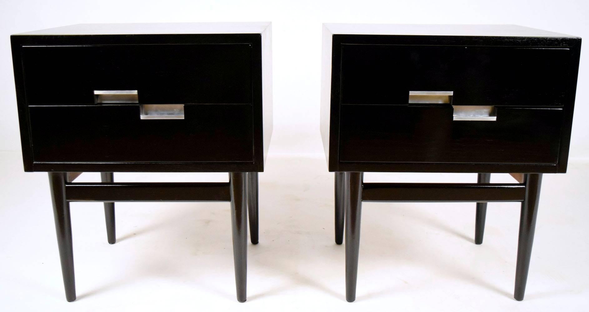This pair of 1960s American Mid-Century Modern-style Martinsville nightstands is made of walnut wood that features a beautiful ebonized finish. The top of the nightstands are made of wood with inlaid aluminium X-shaped details on the corners. There