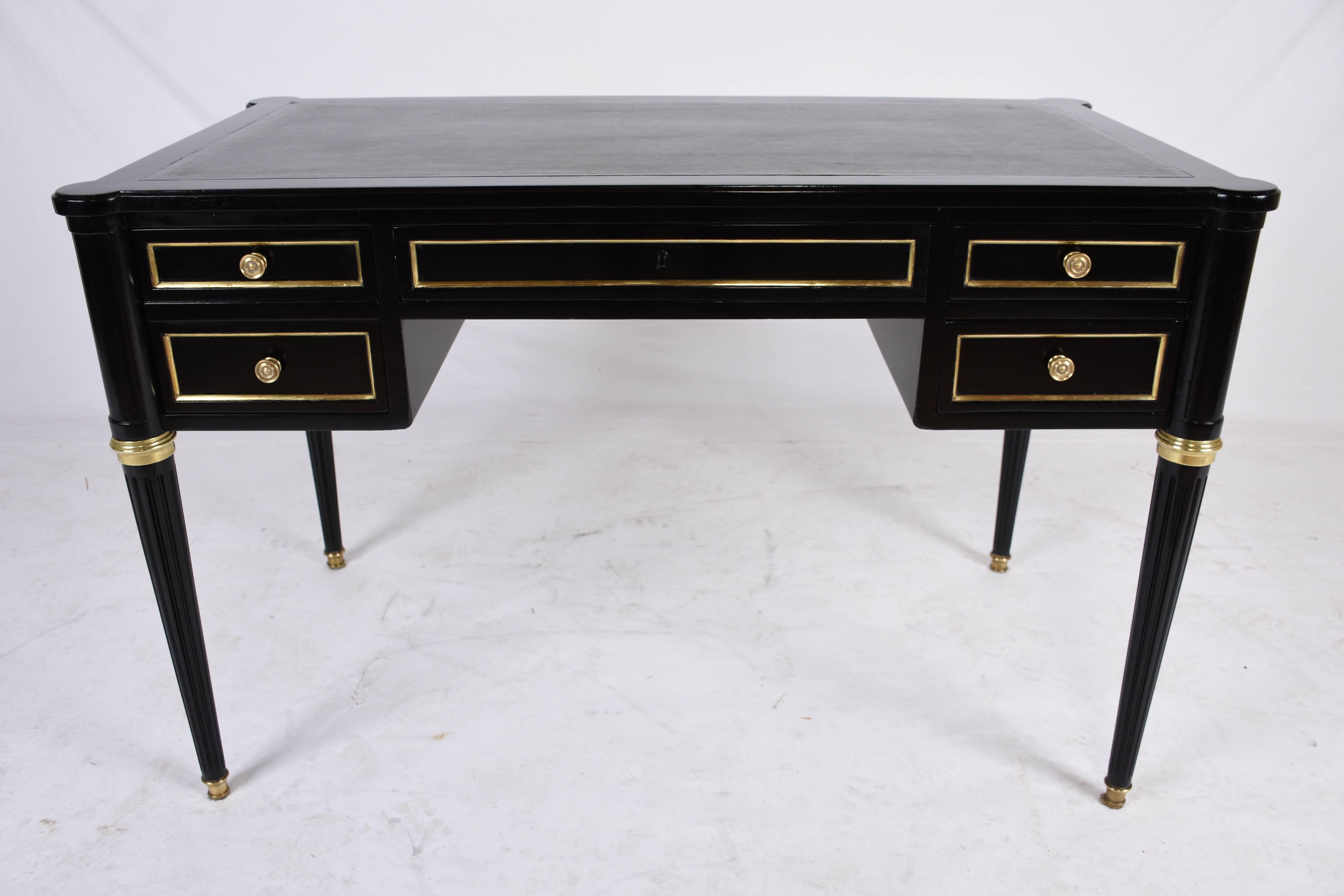 This 1910's Antique French Louis XVI-style desk is made of mahogany wood that has been stained in a rich black color with a lacquered finish. The desk has its original embossed leather working space in a beautiful green color. The facade of five