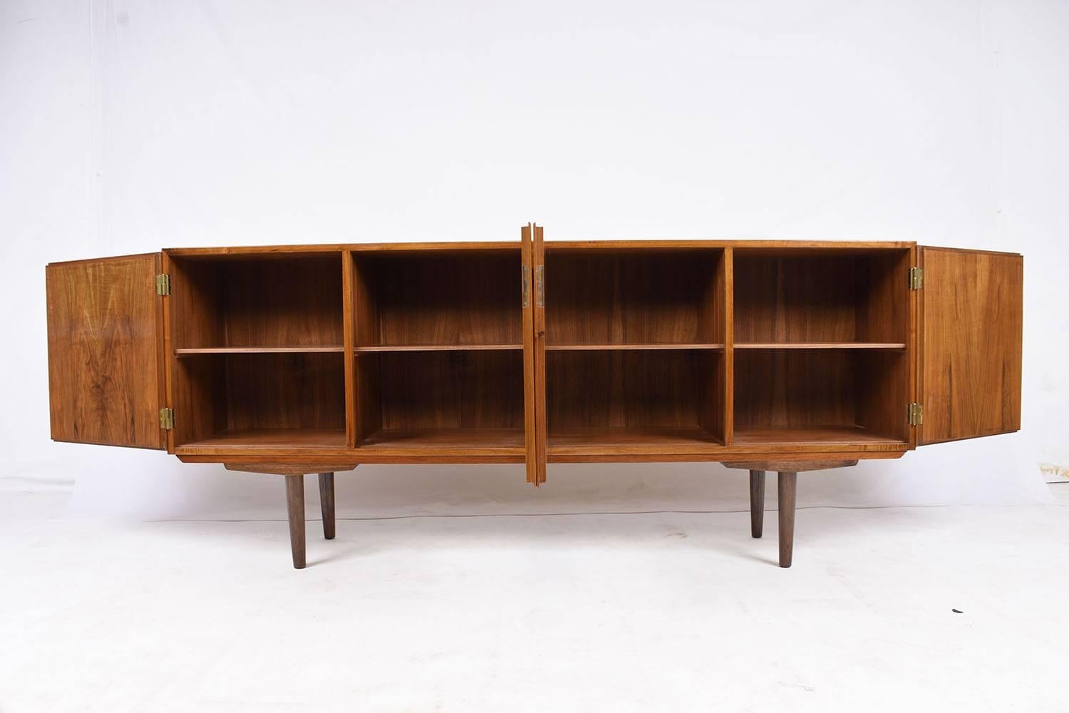 This 1960s vintage Danish Mid-Century Modern-style credenza is made of walnut wood that has been stained in a light wood color with a lacquered finish. The four cabinet doors feature a beautiful patina and a simple brass keyhole and hinges. Inside