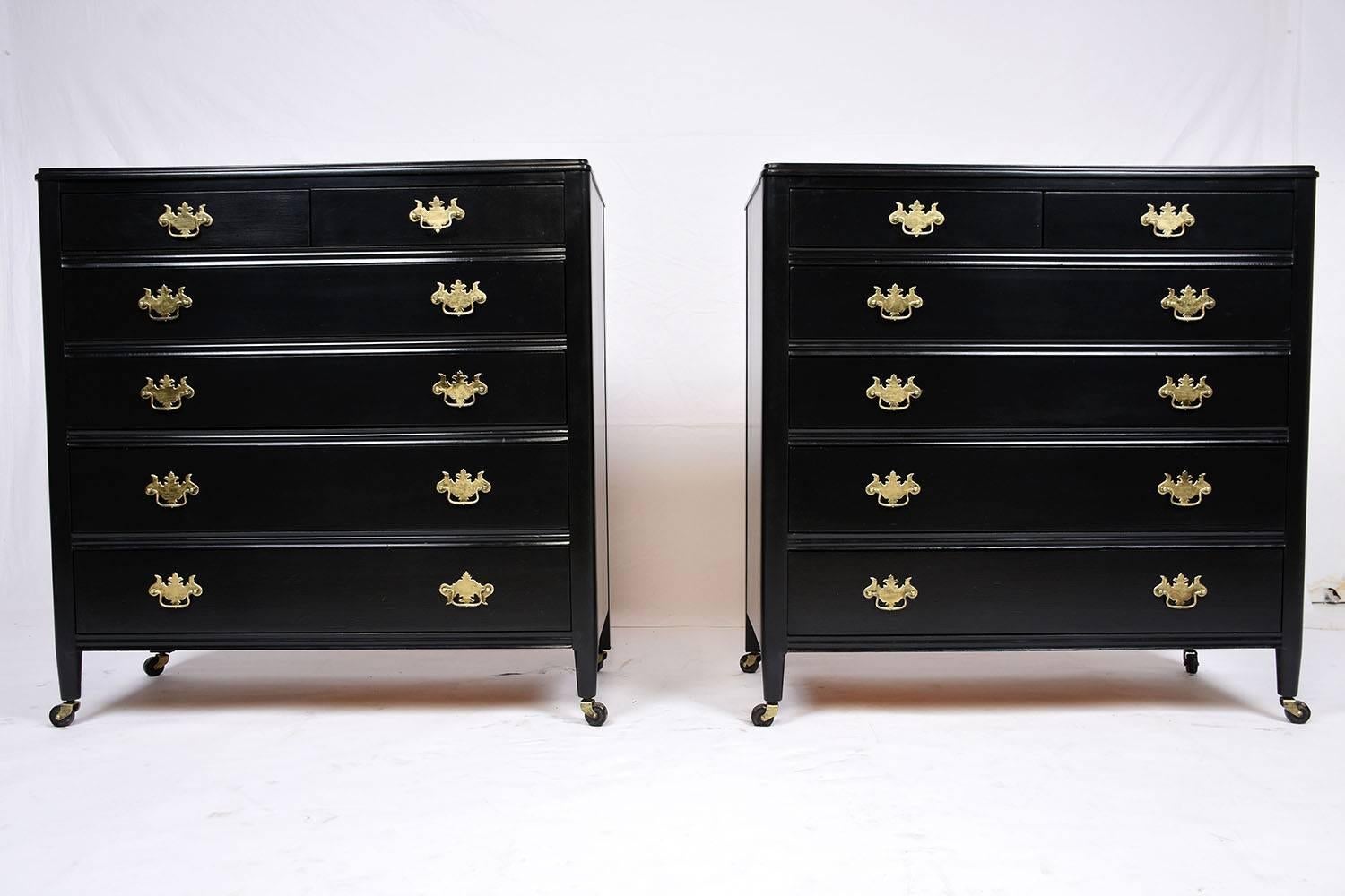 This 1920s antique Regency-style pair of chest of drawers is made from mahogany wood that has been finished in a rich black color stain. These elegant chest of drawers feature two side by side top drawers and four full size drawers below. The facade