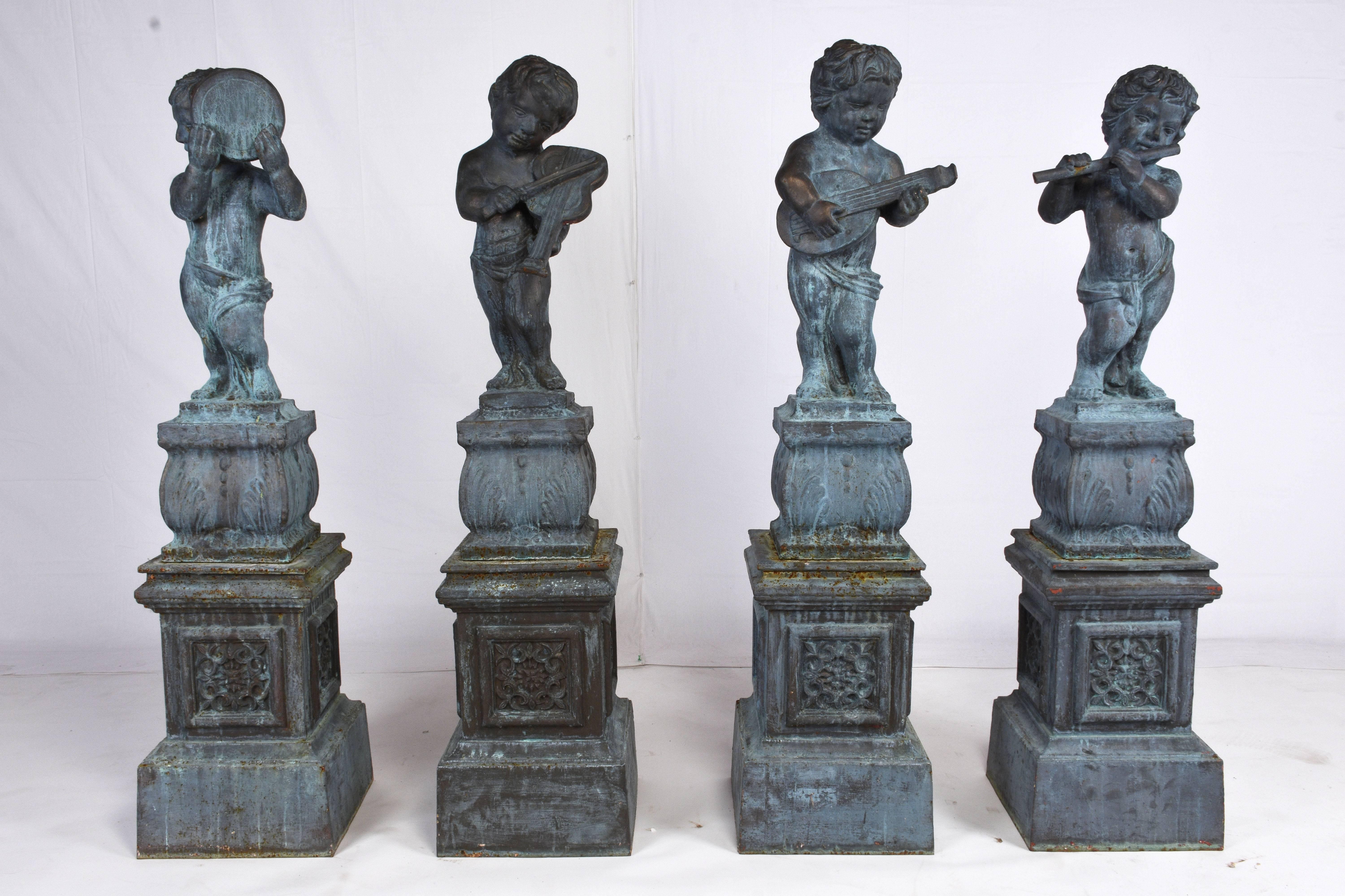 This set of four neoclassical-style garden figurines are made of cast iron and have a natural oxidation finish and the original patine. Each statue features a cherub figurine playing a musical instrument. These figures are cast in a contrapposto