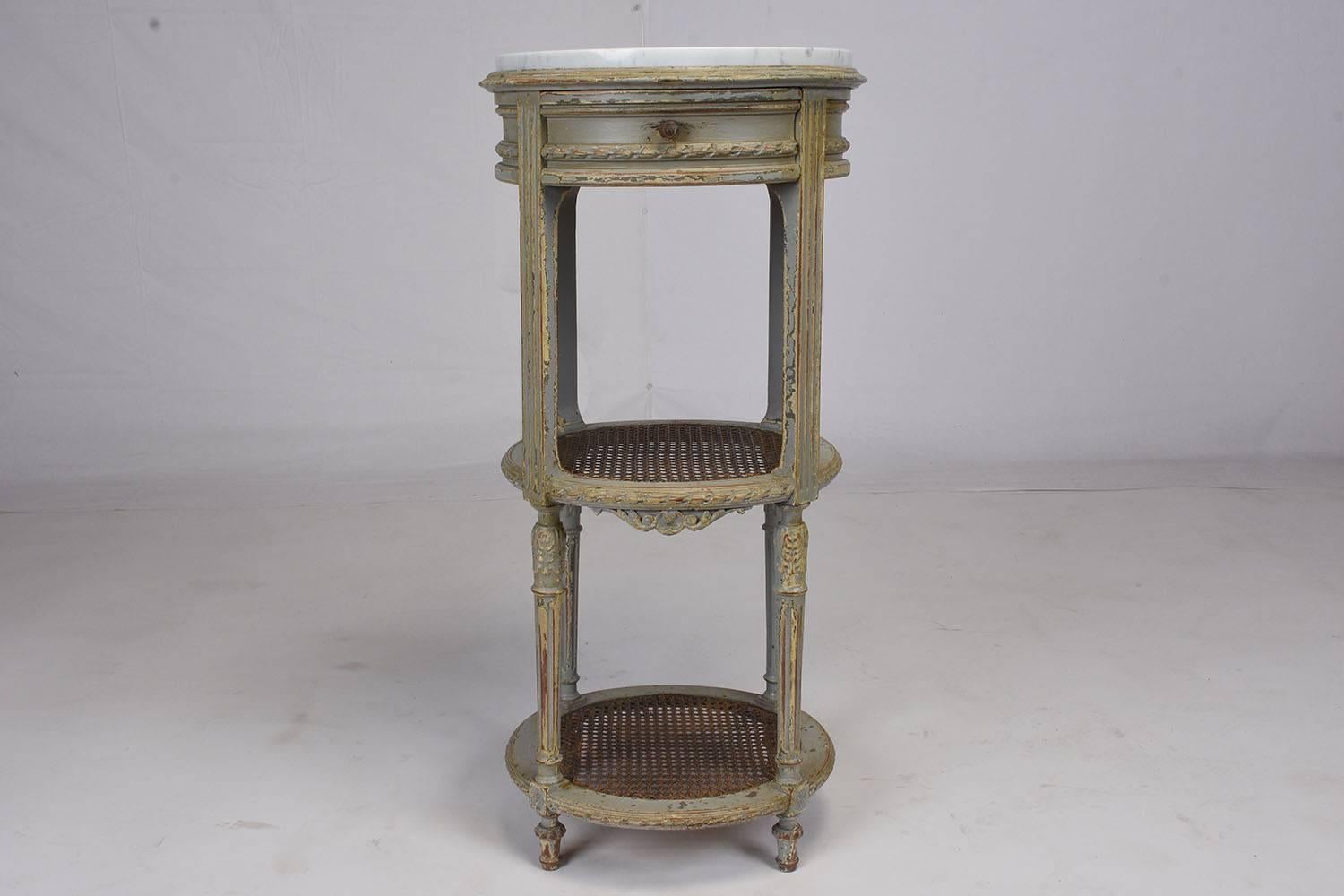 This pair of 1890s French Louis XVI-style nightstands are made for wood that features the original blue and gray color combination with a beautiful distressed finish. The frame features hand-carved details of flowers and garland bands. There is a