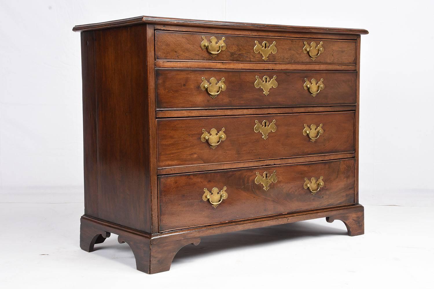 This 1850s antique George III-style chest of drawers is made of mahogany wood that features the original mid-tone color finish. The four drawers are different sizes and feature two decorative brass drawer pulls and a decorative keyhole plate. The