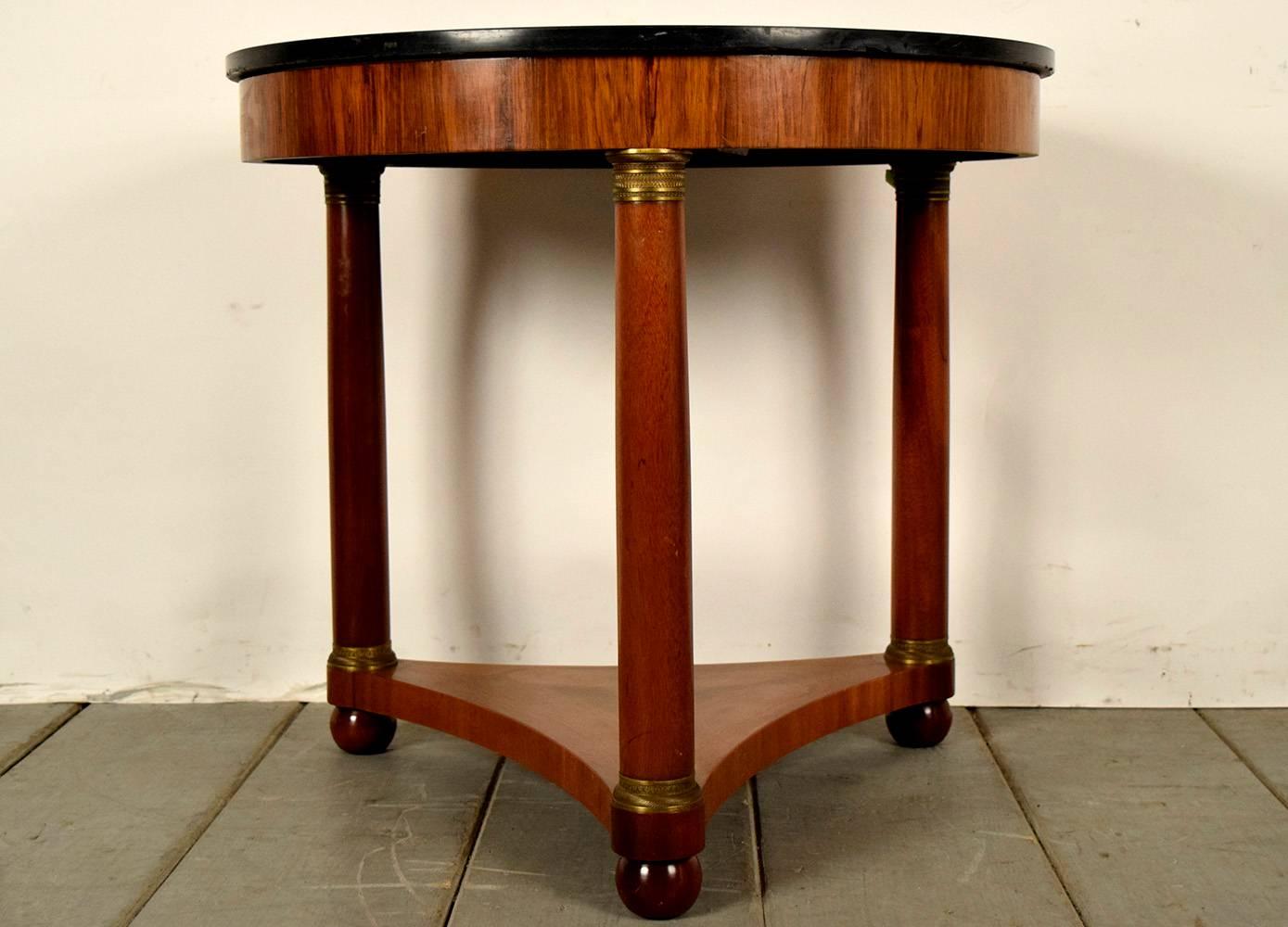 This is a 1900s French round end table. Has a black circular marble-top, solid wood frame, three columns with bronze accents on the top and bottoms and pedestal legs. Table is ready to be used and enjoyed for many years to come.
