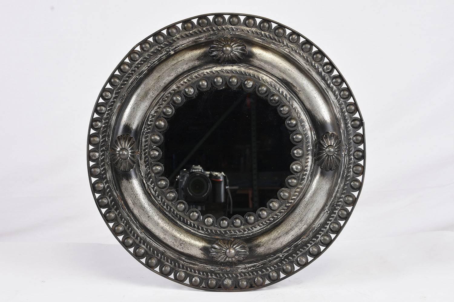 This vintage pair of mirrors features pressed metal frames with decorative elements. Along the edges of mirrors are beaded and rope details with floral accents in the centre of the frame. The mirrors are fully reflective and in great condition. This