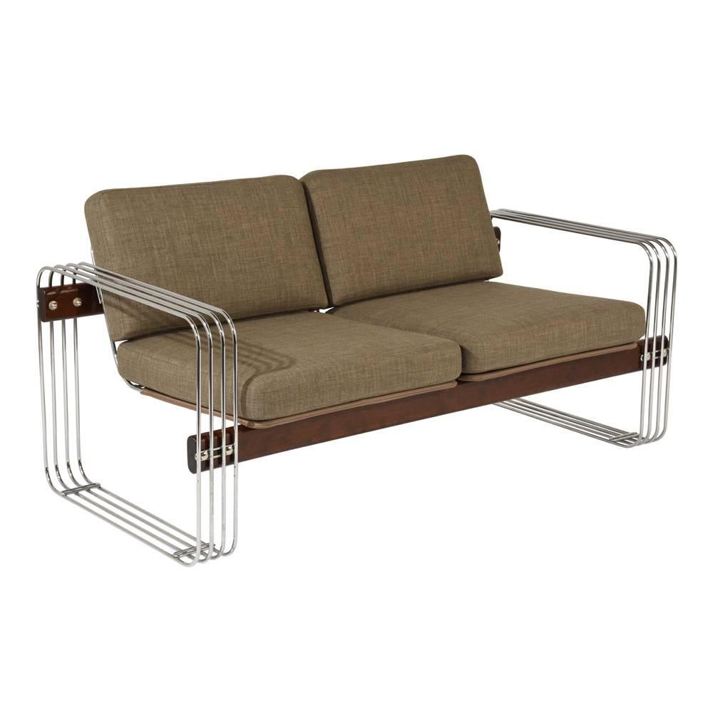 This 1950s Mid-Century Modern-style sofa is designed by Heinz Meier and features a chromed steel base with wood accents. The wood has been stained in a walnut color with a lacquered finish. The removable cushions have recently been professionally