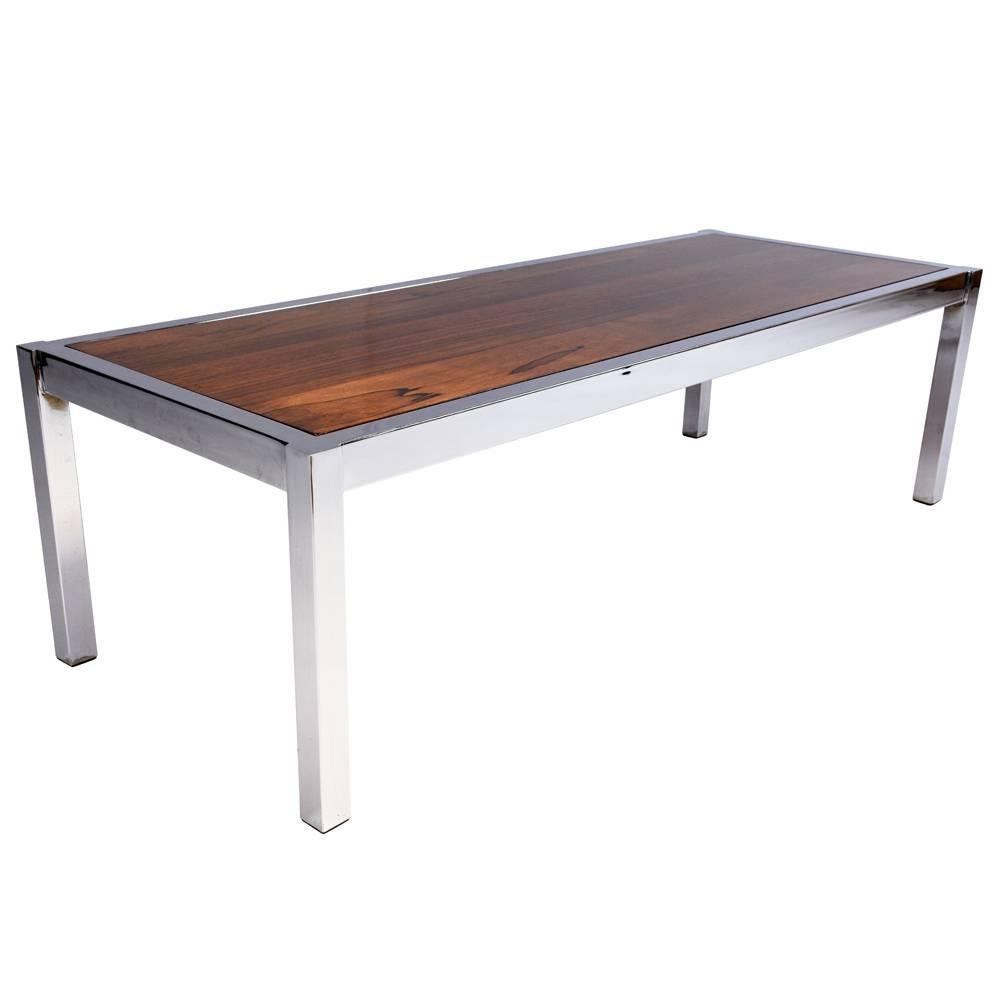 This 1970s Mid-Century Modern-style coffee table features a simple, but elegant chrome frame. The base is highlighted by a rosewood top with a rich stain and a lacquered finish. This coffee table is sturdy, stylish and ready to be used in any home