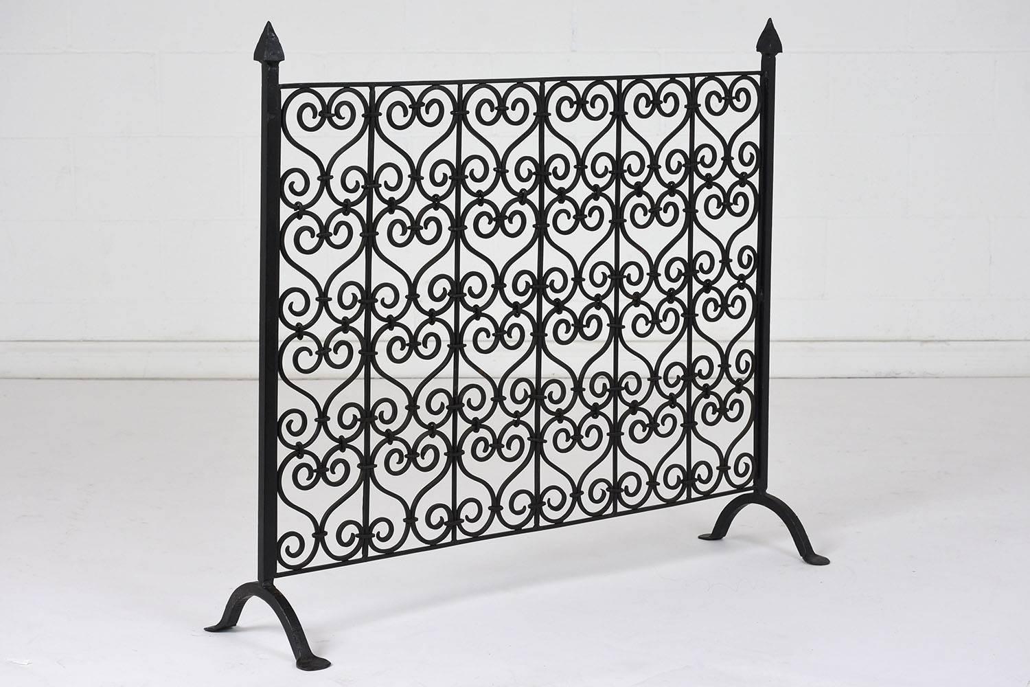 This 1900s French Baroque-style fireplace screen is made of wrought iron with a dark finish. The screen features a repetitive S-shaped scroll pattern. The ends have a pointed arrow finial and flat footed arched feet. This fireplace screen is sturdy,