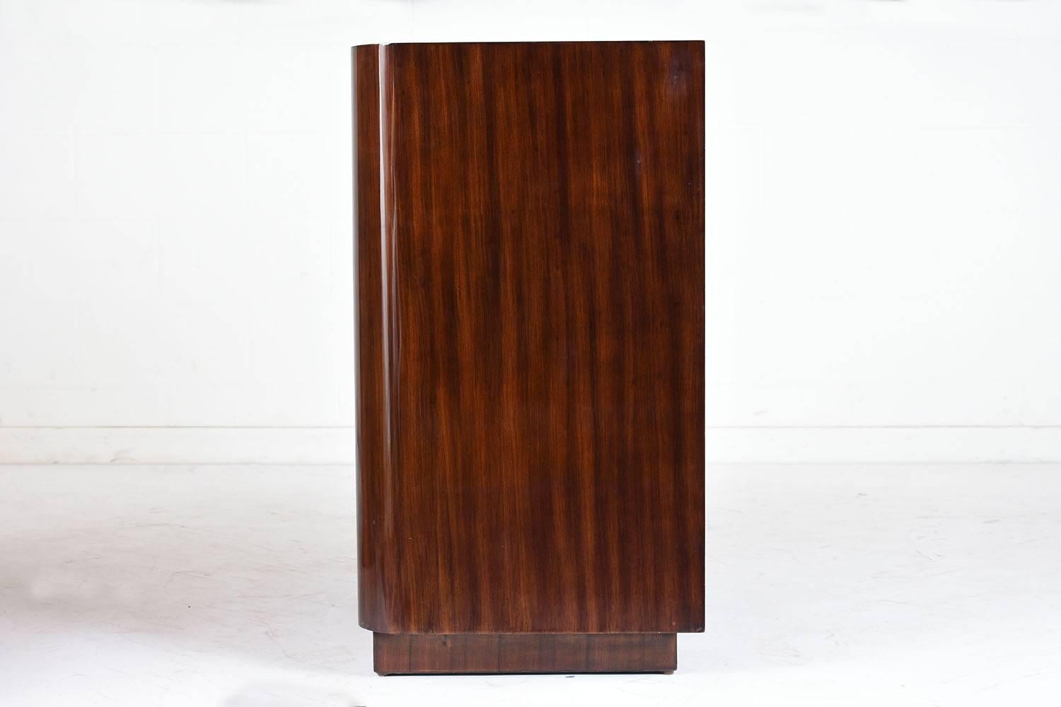 This 1990s Modern-style chest of drawers is designed and made by Ralph Lauren. The chest of drawers is adorned with macassar wood veneers and features a high gloss lacquered finish. The sleek design of this chest features rounded back edges and a