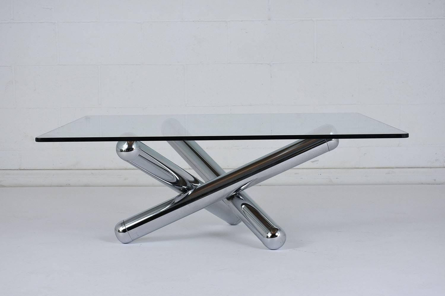 This 1970s Mid-Century Modern-style coffee table features an atomic shaped chrome base. The chrome base has three rounded arms that overlap and create a unique sculptural base. The table features a 1/2