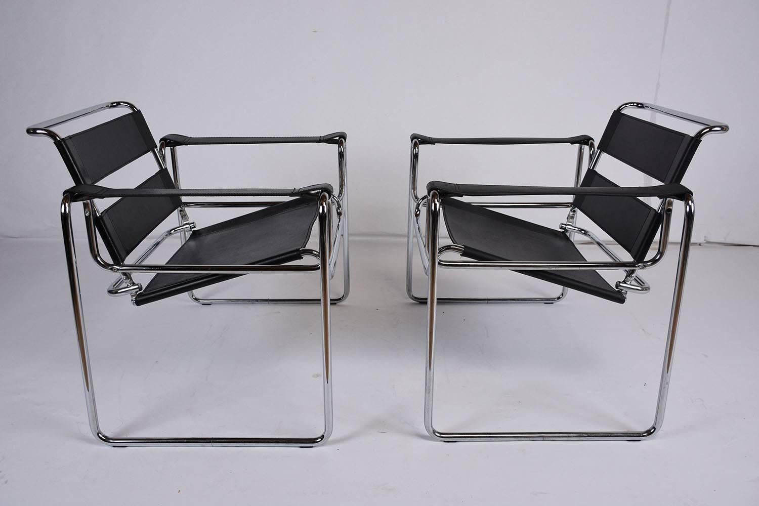 This unique set of 1970s vintage Mid-Century Modern style lounge chairs are crafted in the image of the wider known Wassily style. These chairs feature minimalistic chrome frames with black leather bands that create the seat, seat back, and arm