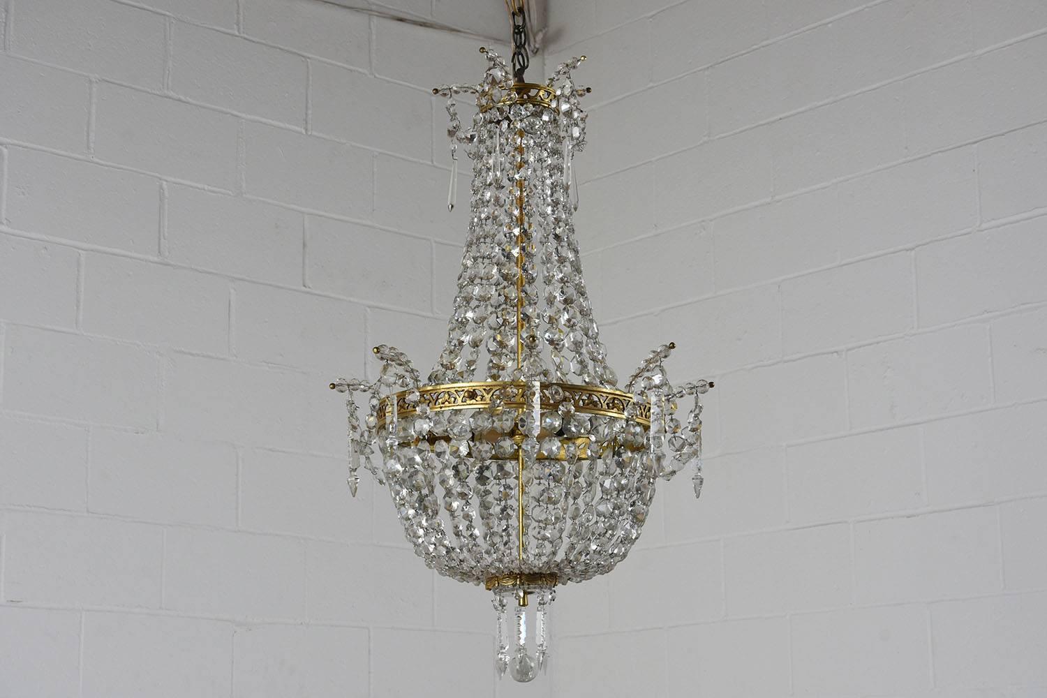 This stunning Antique Hollywood Regency Basket Chandelier is made of brass with crystal accents and the upper and center bands have leafy cut-out decorations with the bottom band is decorated with carved fabric swags and tassels. The Italian