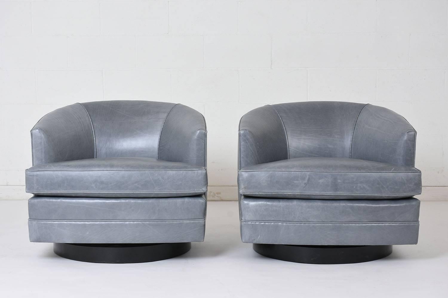 This pair of 1960s Mid-Century Modern style lounge chairs is made in the manner of Milo Baughman. The chairs have recently been upholstered in a blue gray leather fabric with single piping trim details. The chairs have a single removable cushion