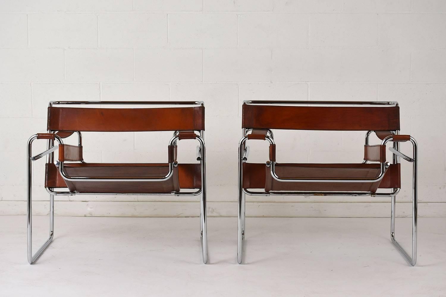 This pair of 1960s Mid-Century Modern Wassily chairs are designed by Marcel Breuer. The chairs feature the iconic frame shape made of steel with a chrome finish. The seats have the original leather straps and seat finished in a rich brown color with