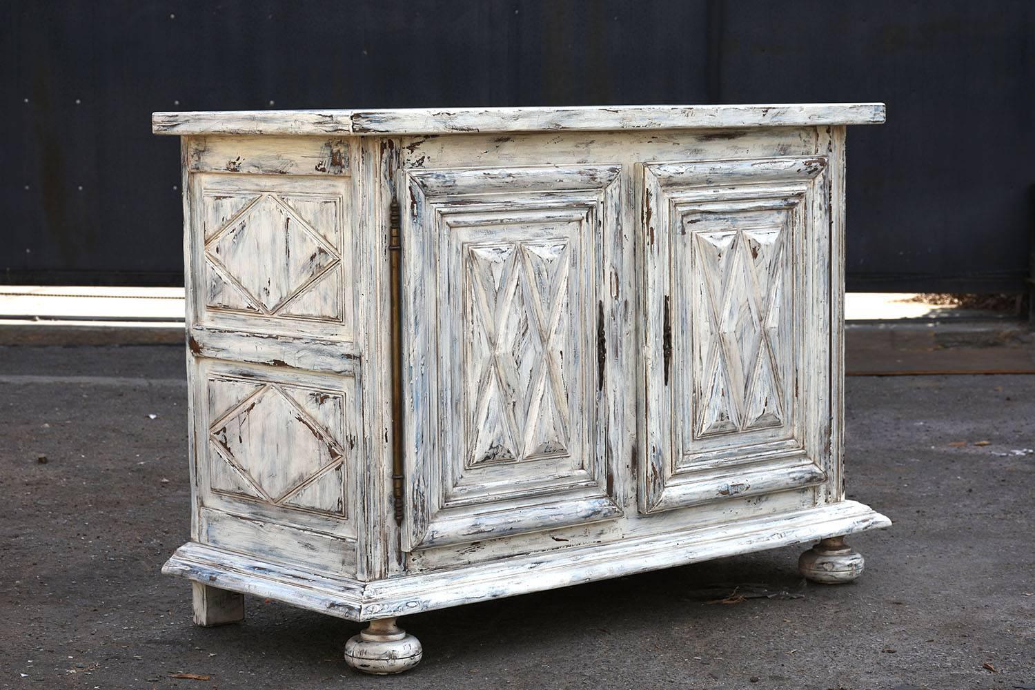 This 1900's French Renaissance-style buffet is made of walnut wood painted in an off-white and blue color combination with a distressed finish. The buffet has a wood top and features carved moulding details throughout. The cabinet doors and the