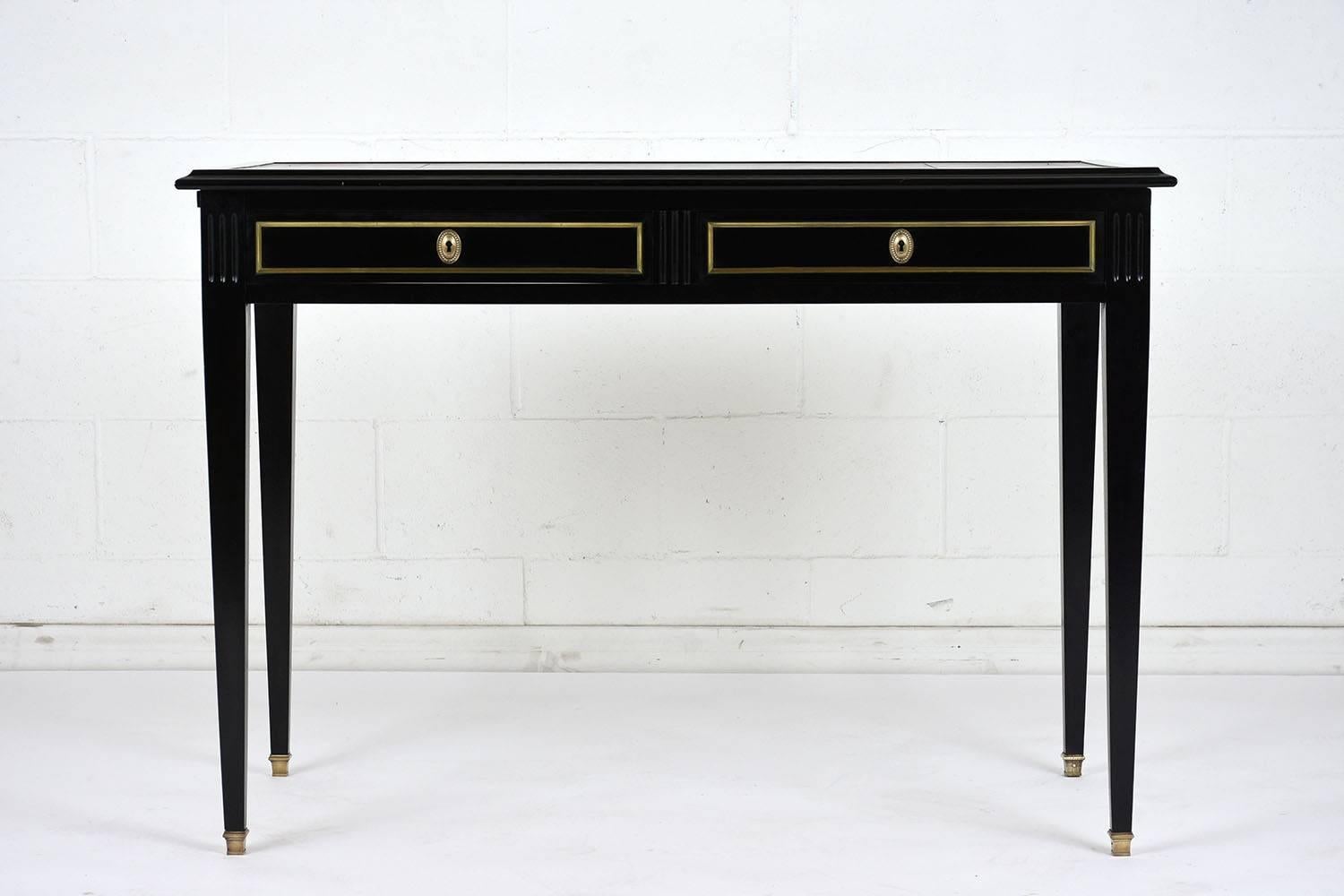 This 1900's French Louis XVI-style mahogany desk has been stained a rich black color with lacquered finish. There are two drawer with brass moulding and keyhole plates. The top of the desk has a brown embossed leather work area with gilt trims.