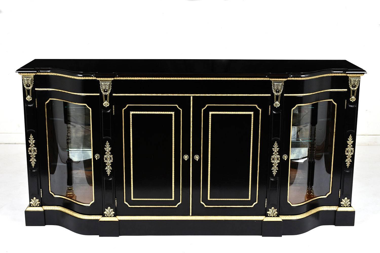 This 1970's Louis XVI-style Buffet is made by Henredon features an ebonized and lacquered finish with gilt moulding and brass ormolu decor. The center section has two cabinets with brass molding details and a hidden drawer and shelf inside. The