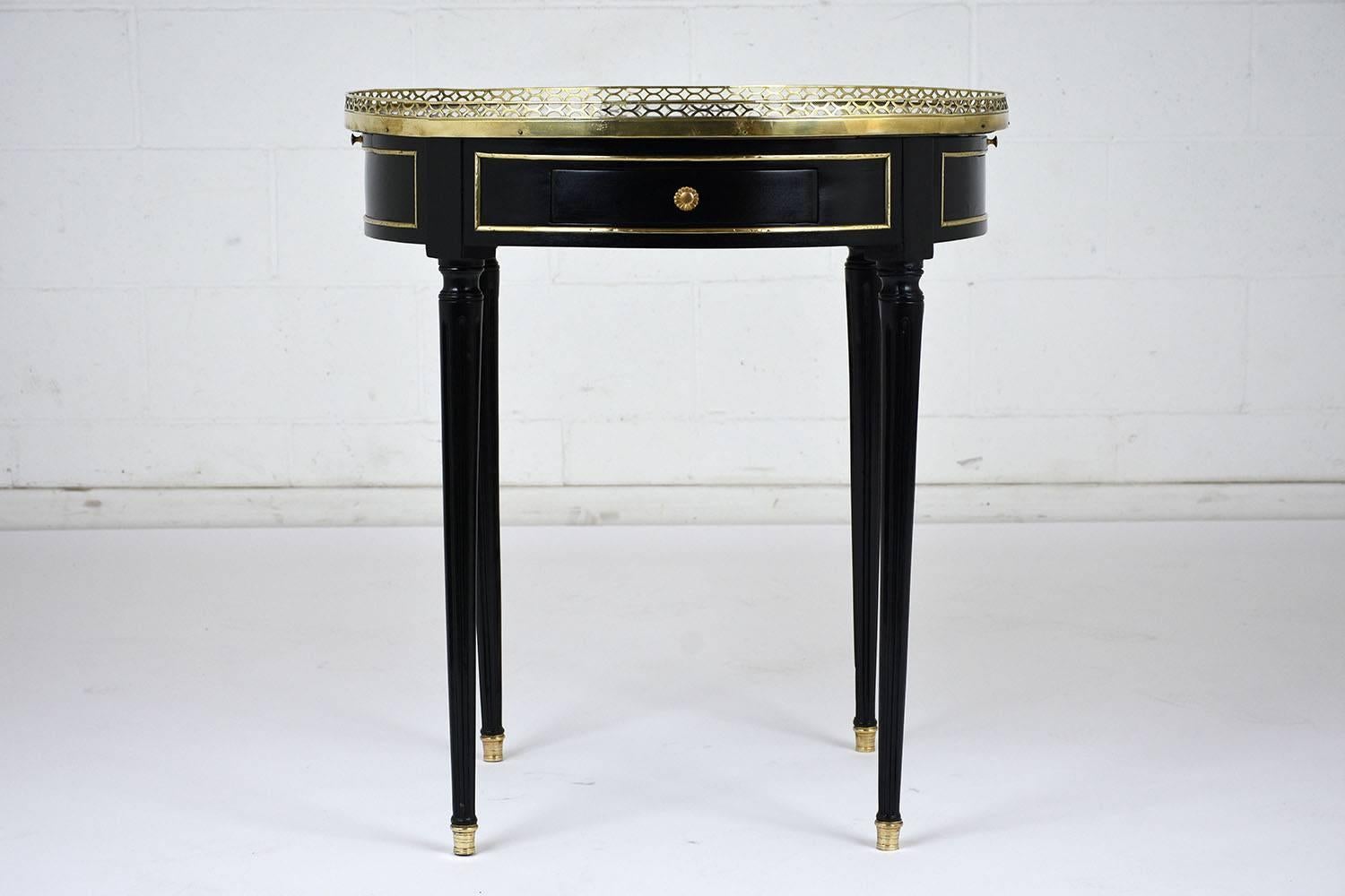 This 1900s Louis XVI-style end table features an ebonized mahogany body with a lacquered finish and brass moulding details. There are two drawers on opposite side of the table with a decorative brass knob. Also there are two shelves with embossed