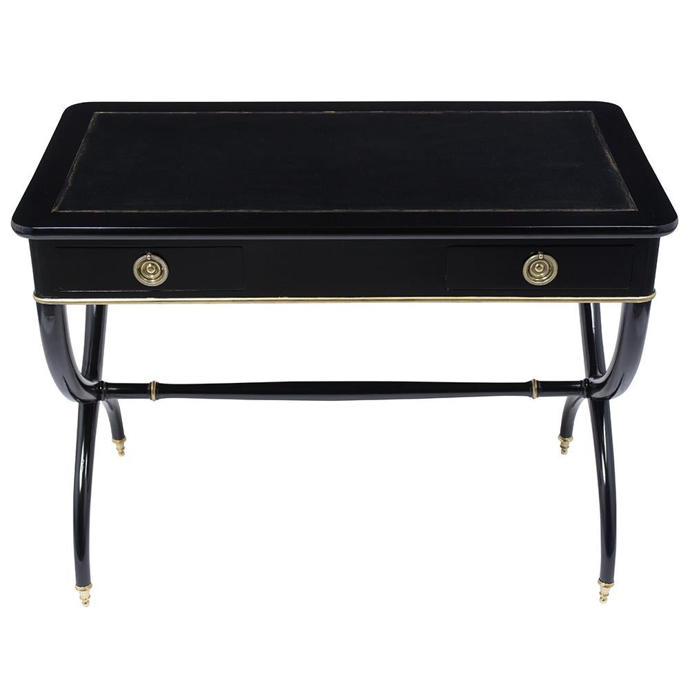 A Remarkable Antique French Empire Writing Desk finely handcrafted out of mahogany wood that has been stained in an ebonized color with gilt molding details and newly lacquered finish. This beautiful writing table features a black leather top with