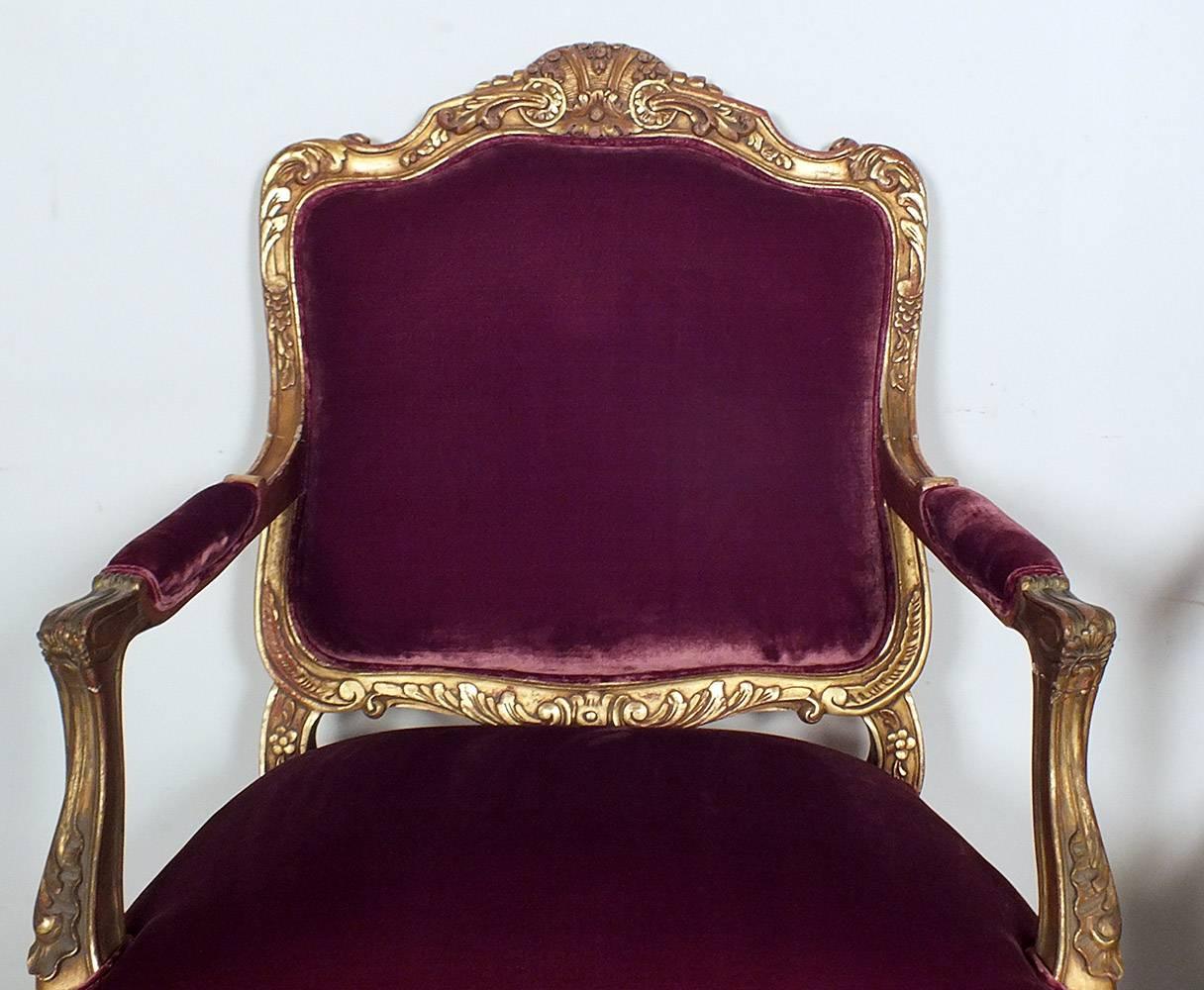 This elegant pair of French giltwood Louis XV Bergeres is made with solid wood frames. On the frames there are hand carved decorations throughout of leafs, sea shells, flowers and scrolls finished in a gold color. Both chairs have been recently