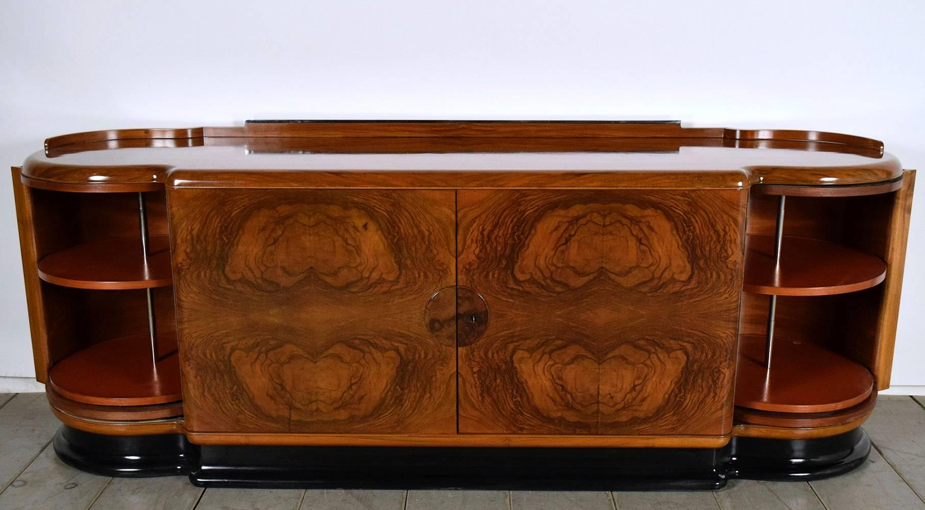 This elegant Art Deco-style buffet or bar is made of solid wood construction and covered with beautiful exotic burl and walnut veneers with a lacquered finish. The front features two circular revolving doors on the sides that each have a Lazy Susan