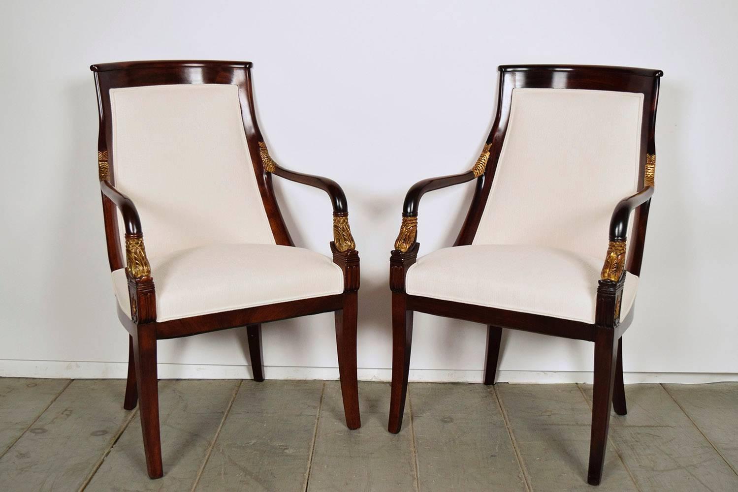 Set of 12 beautiful Regency-style mahogany dining chairs. Solid mahogany wood construction, with its original mahogany color finish and gilt accent color on the arms. Has elegant curved backs and stylish carved arms. All chairs have been newly