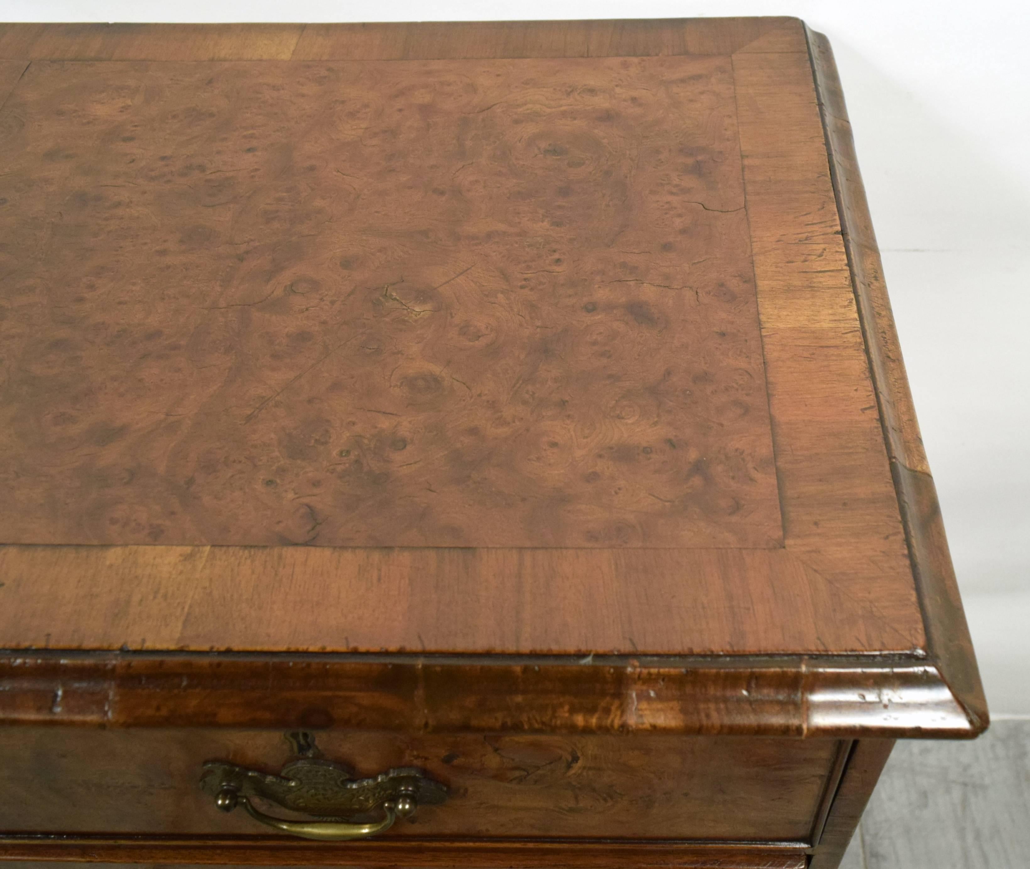 This is a gorgeous late 18th century English George II chest of drawers. It is made from solid wood covered with burl veneers. It has five drawers, two small ones on top and three long ones underneath. It also has shaped bracket feet under a quarter
