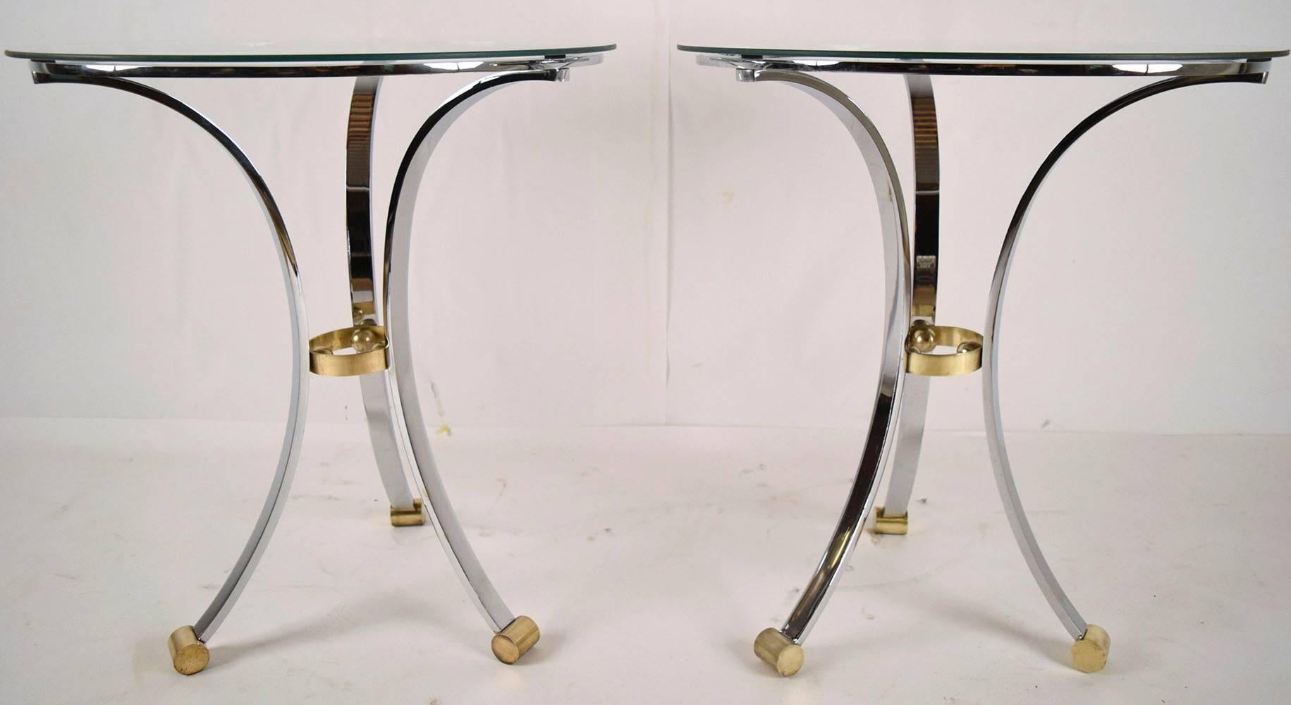 This pair of 1970's Mid-Century Modern Maison Jenson round End Tables features a solid chrome frame with a brass ring connecting the legs in the center and brass feet. The tables have round glass tops that rest upon the base. Both tables are in