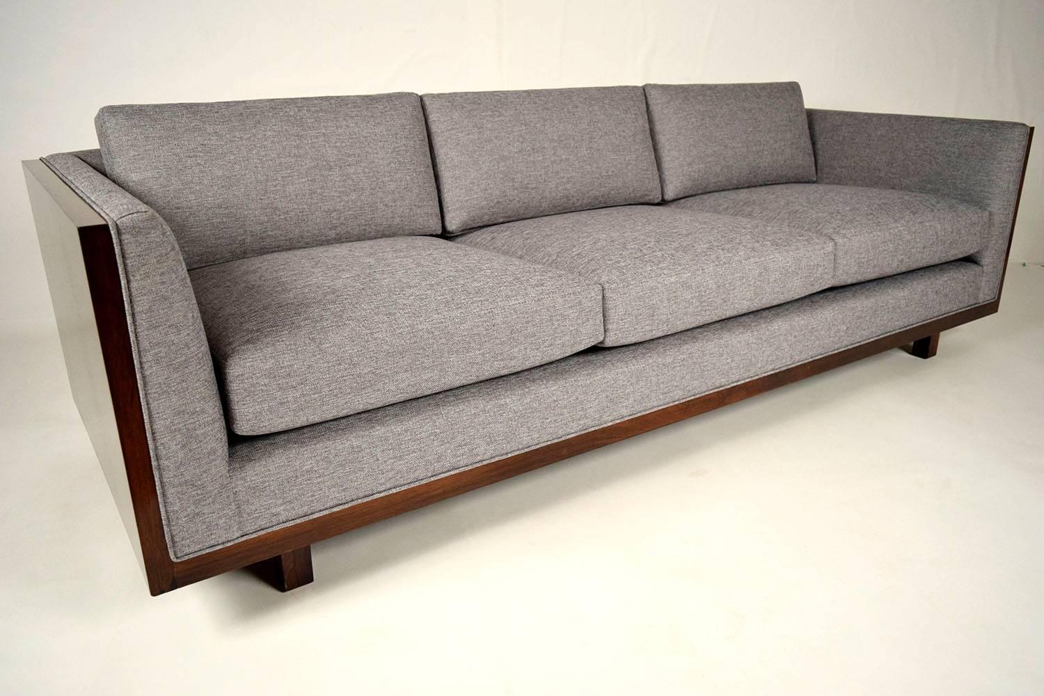 This is a elegant 1950s Milo Baughman Cube sofa. Wood frame has been newly refinished in a dark walnut color with a lacquered finish. Professionally reupholstered in a gray fabric with single piping trims. Has three back pillows and three seat