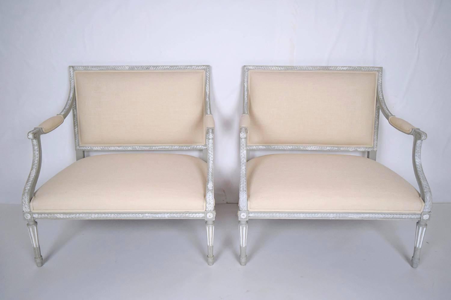 Pair of 1900s French Louis XVI bergeres. Solid walnut wood frames, hand-carved, newly painted in a gray with a distressed finish. Professionally upholstered in a ivory color linen fabric with double piping trims. Finished with carved fluted legs and