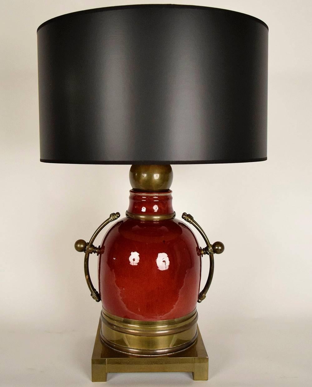 This beautiful pair of Oriental-style table lamps have red colored ceramic bodies with brass handles and brass square base. Both lamps are accompanied with new black paper fabric shades. These lamps have been recently wired and are ready to b in