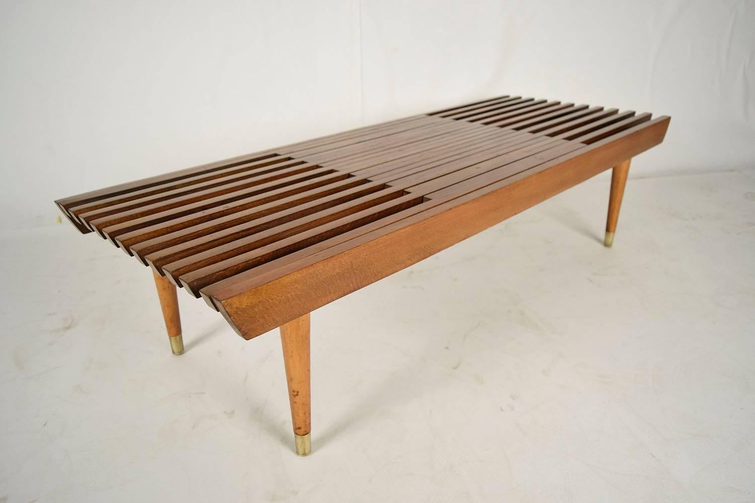 This is a 1950s Mid-Century Danish slatted bench. Solid teakwood, with original finish. Bench extends to 60 inches long, when closed measures 48 inches. Finished with cone legs and brass caps. Bench is solid and sturdy, ready to be used.
