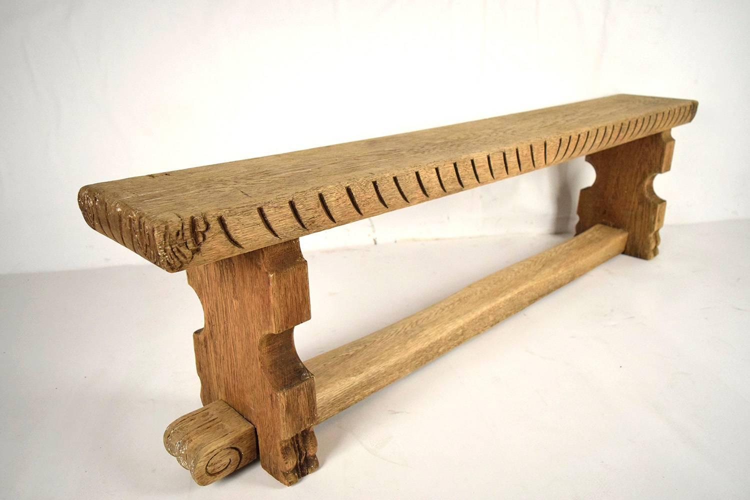 This is a beautiful 1890's hall bench made of solid oak wood in a bleached wood color. The bench is adorned with hand-carved designs on the sides, and the stretched legs. This bench is solid and sturdy, ready to be used for years to come.