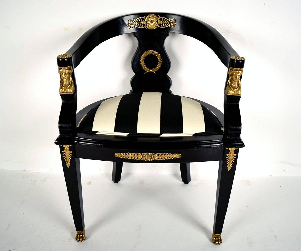 Elegant ebonized 1870s Empire armchair. Solid mahogany wood, newly finished in a rich black color. Has a low curved back, that ends at the arms. Bronze ornaments complement the back, arms, bottom center, and legs. Seat has been professionally