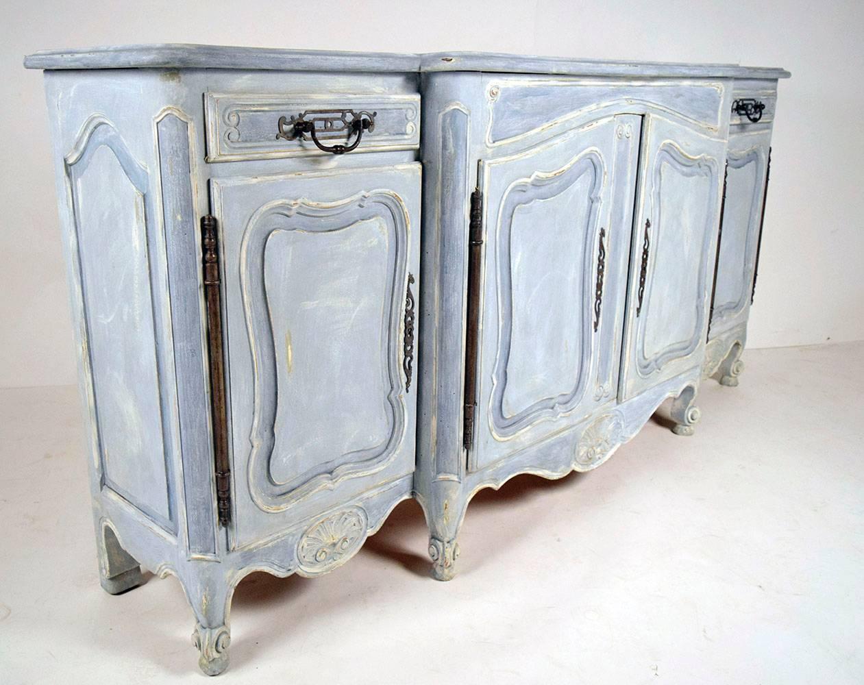 This is a one of a kind 1900's Louis XV sideboard or credenza. The buffet is made of solid oak wood that has recently been painted in a blue and off-white color combination, with a beautiful distressed finish. There is a beveled wooden top with two