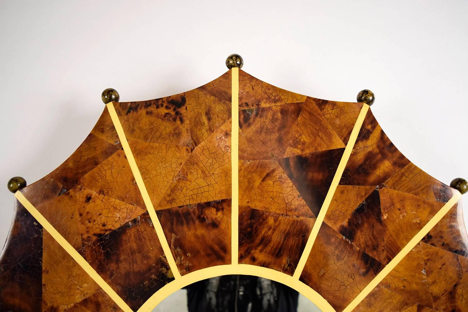 This unique 1970's starburst wall mirror features a solid wood frame that is covered in faux tortoise shell veneers. The tortoise shell veneers are separated by a thin yellow divider that is accented with round wood balls. The piece is accompanied