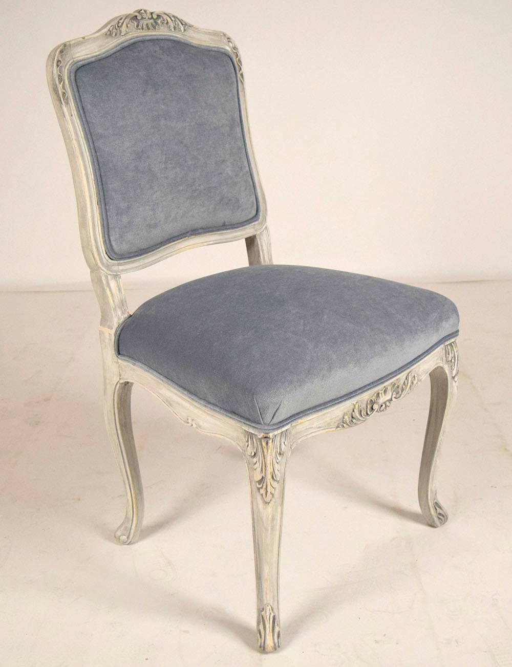 Set of eight French dining chairs. Solid walnut frames with carvings all throughout the top, sides, front, bottom and legs. They have been painted in a gray and oyster color combination with a beautiful distressed finish. All chairs have been