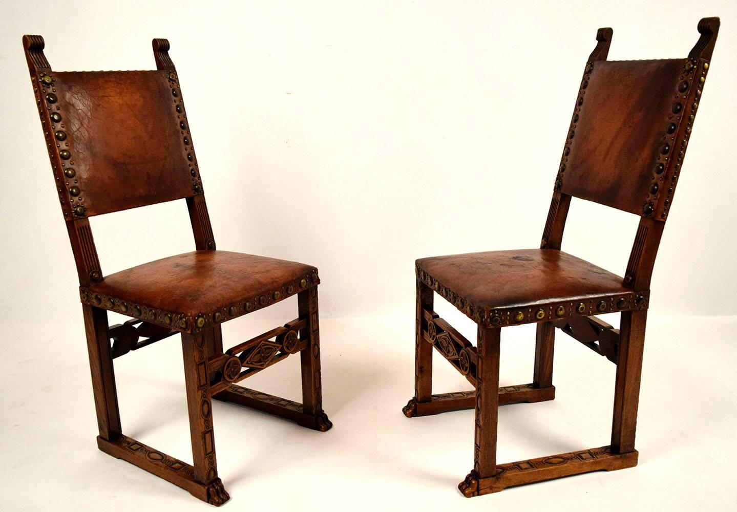 Set of six antique Spanish revival dining chairs. Oakwood frames with original dark walnut finish. Carvings throughout the frame and engraving wood on the stretched legs. Back and seat are upholstered with original distressed leather with nail-head
