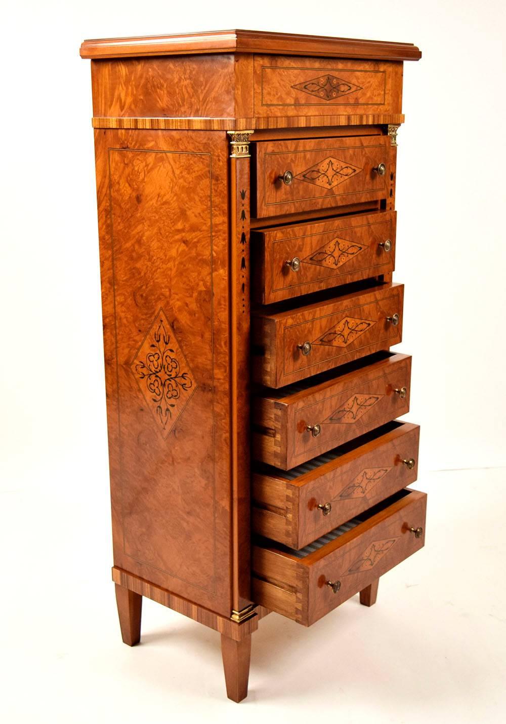 This beautiful 1970s chest of drawers is made of solid wood with beautiful inlaid designs on the top, sides, and on the front of the drawers. The chest features seven drawers and the top drawer uniquely opens from the bottom. The rest of the six