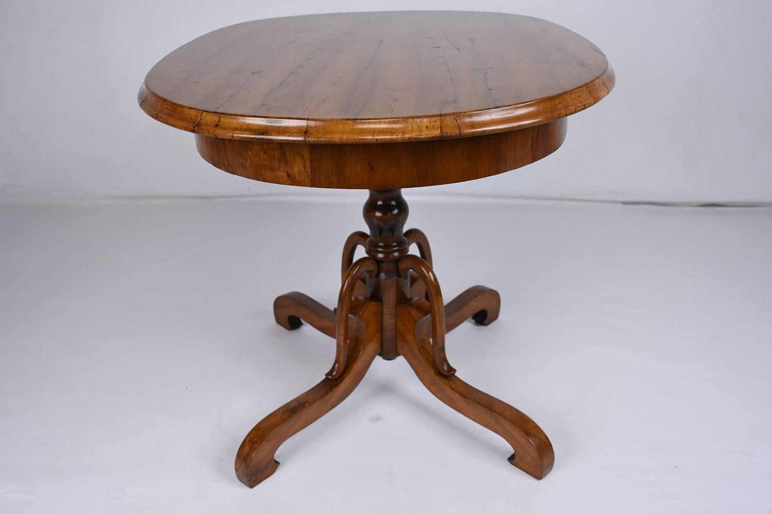 This stunning 1830s antique French Louis Philippe-style centre table is made of walnut wood with its original finish. The oval shaped table is wonderfully carved and features a great natural patina. The pedestal legs are uniquely carved with scroll