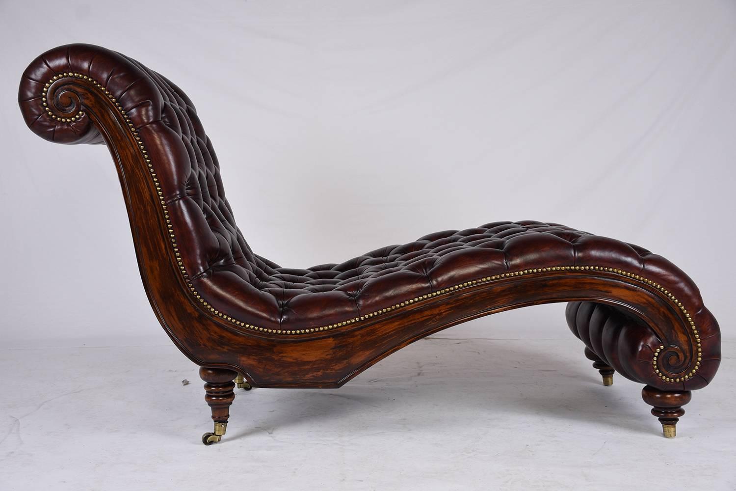This 1980s vintage Chesterfield chaise lounge features a wood frame that has been stained in a rich mahogany color and a polished finish. Adorning the wood are simple carved moulding and scroll work details. There is a single drawer at the base of