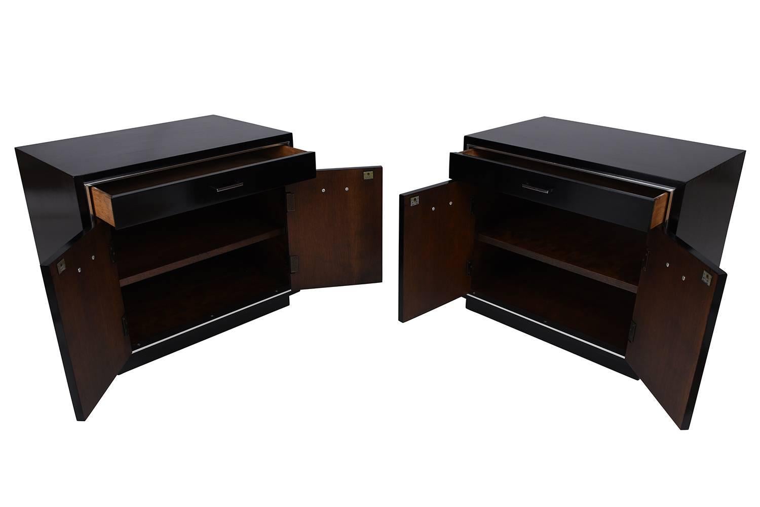 This 1960's Mid-Century Modern Pair of Nightstands are made out of walnut wood with a new ebonized lacquer finish. The nightstands are adorned with chrome delicate molding, come with a single top drawer and two cabinet doors below with chrome