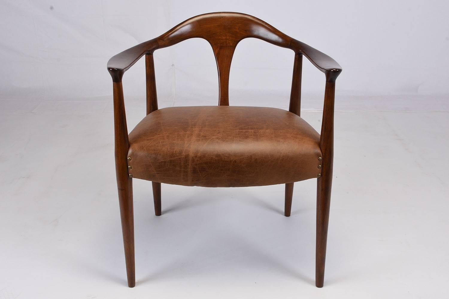 This 1960s Mid-Century Scandinavian armchair is made of teak wood that has been stained in a rich walnut color finish. The carved wood frame is shaped with a curved back and tapered legs. The comfortable seat has recently been professionally