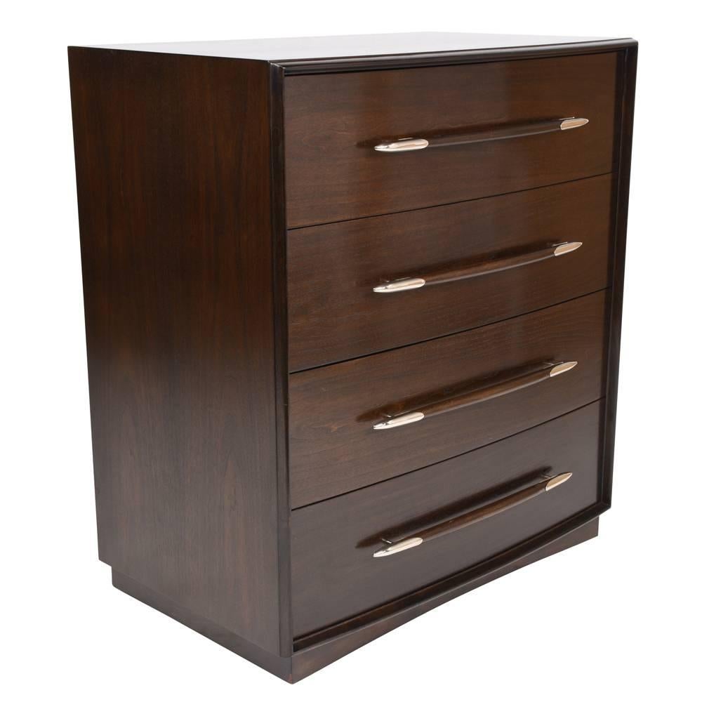 This 1960s Mid-Century Modern-style chest of drawers is designed by T.H. Robsjohn-Gibbings for Widdicomb. The beautiful wood has been stained a rich, dark walnut color and a lacquered finish. The four drawers are adorned with large wood with steel