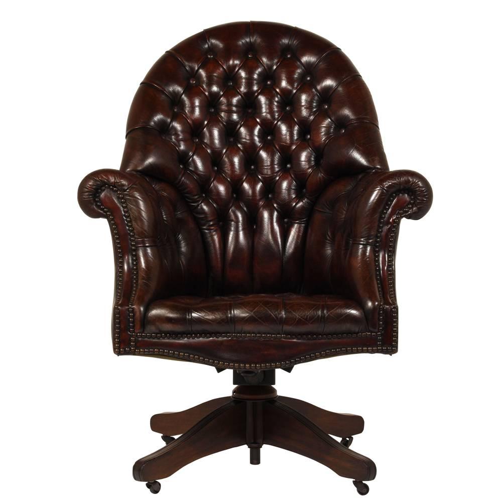 This 1950s Regency-style office chair is fully upholstered in leather that has been dyed in a rich burgundy color. The leather has tufted details on the seat and arm and is adorned with brass nailhead trim. The carved wood base has been stained in a