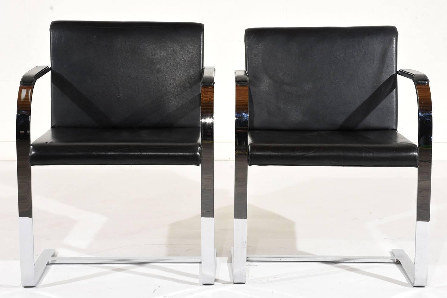 This pair of 1960s Mid-Century Modern flat bar Brno chairs by Mies Van Der Rohe feature a sleek chrome frame and leather upholstery. The floating frame is sturdy and supported by a stretched bar at the bottom. The seat and armrests feature the